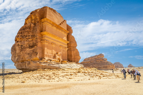 Group of tourists in front of Tomb of Lihyan, son of Kuza carved in rock in the desert,  Mada'in Salih, Hegra, Saudi Arabia