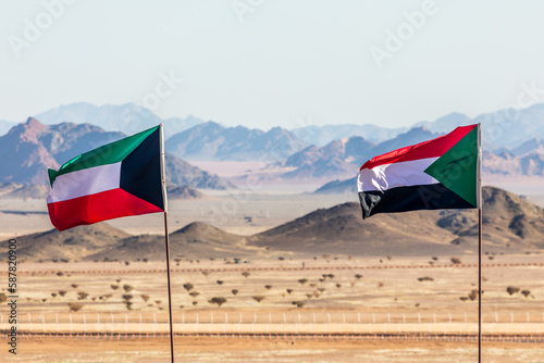 Kuwaiti and Sudanese flags waving togetner on the wind in Saudi Arabian desertwith mountains in background, Al Ula, Saudi Arabia