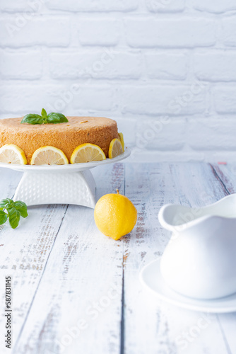 Basil and lemon cake in front of a white brick