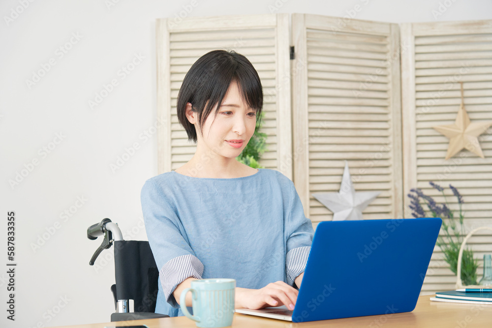 リビングでノートパソコンを使う車椅子に乗った女性