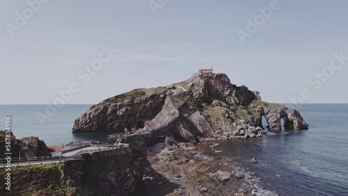 Aerial footage over Gaztelugatxe islet on the coast of Biscay at sunset. It stood for Dragonstone island, with a digitally created castle. Cinematic Flight over man made 231 steps stairs path.  photo