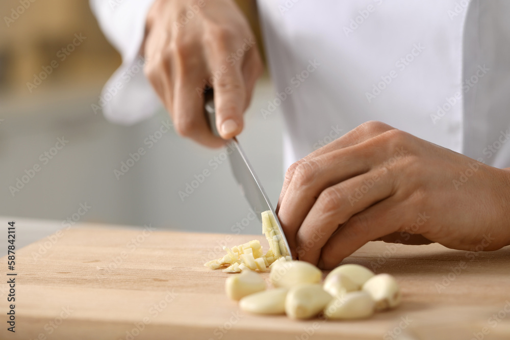 Professional chef cutting garlic at table indoors, closeup Professional chef cutting garlic at table indoors, closeup