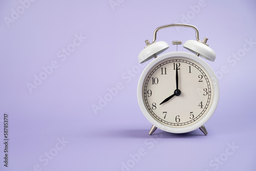 Retro alarm clock on purple or violet table background, vintage style, flat lay
