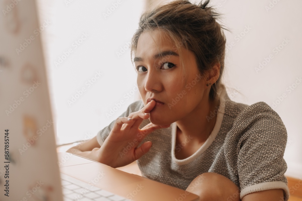Serious asian woman working with her laptop in the bedroom. Serious asian woman working with her laptop in the bedroom.