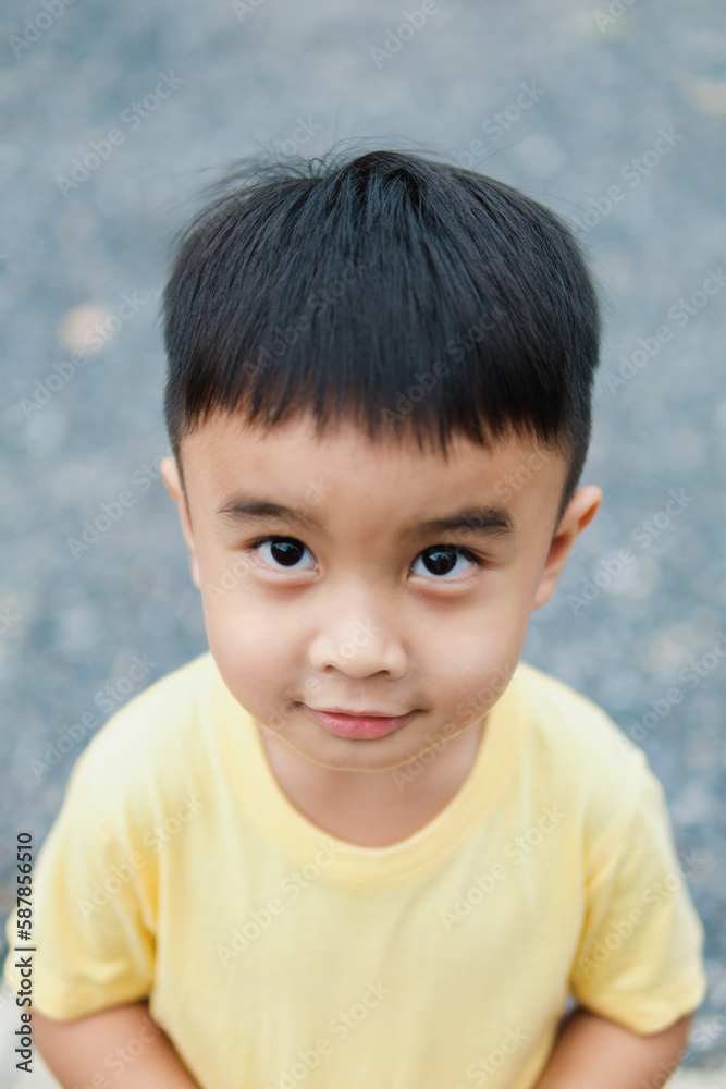 Portrait of an Asian boy wearing a yellow t-shirt. Blurred background.