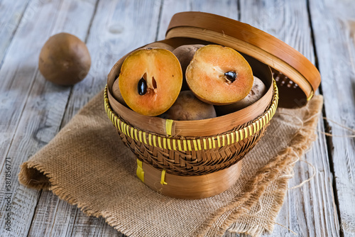 sawo or sapodilla fruit in basket on the wooden table
 photo