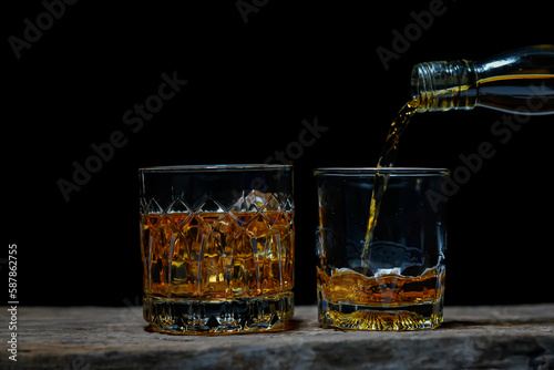 Pouring alcohol into glass, black background