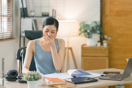 While working from home, a stressed businesswoman appears to be overwhelmed, tired, and worried.