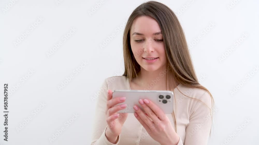 beautiful long-haired girl of European appearance with Brown hair make purchases via smartphone over white background. High quality 4k footage beautiful long-haired girl of European appearance with Brown hair make purchases via smartphone over white background. High quality 4k footage