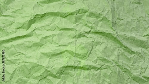 Stop motion photography animation concept. Close-up of crumpled paper of green color. Textured abstract background with copy space.
