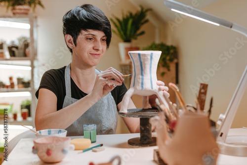 Young woman artisan painting a vase at workshop