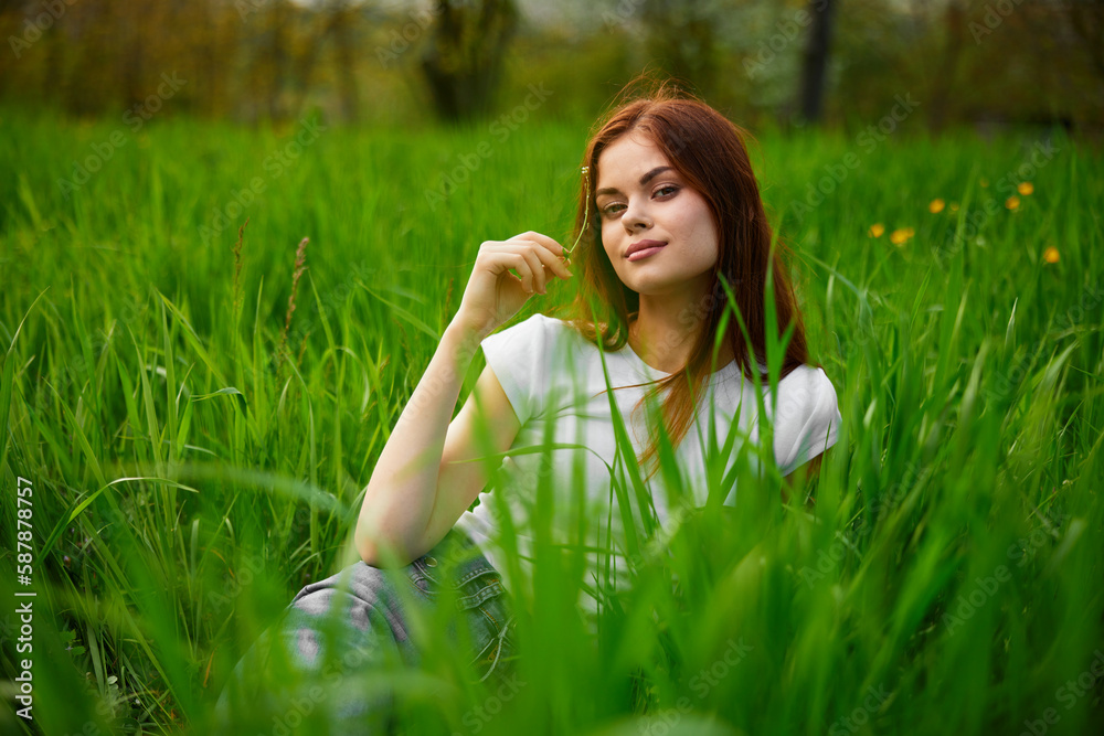 happy redhead woman sitting in green grass during sunset happy redhead woman sitting in green grass during sunset