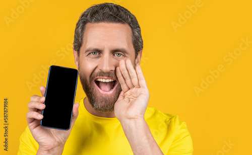 man showing smartphone app isolated on yellow, advertisement.