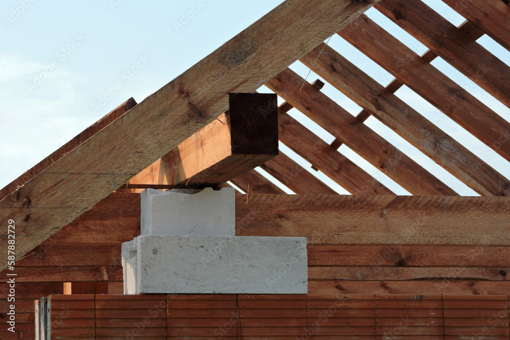 Wooden rafters and a wall plate, walls made of autoclaved aerated concrete blocks, a reinforced concrete beam, blue sky in the background Wooden rafters and a wall plate, walls made of autoclaved aerated concrete blocks, a reinforced concrete beam, blue sky in the background