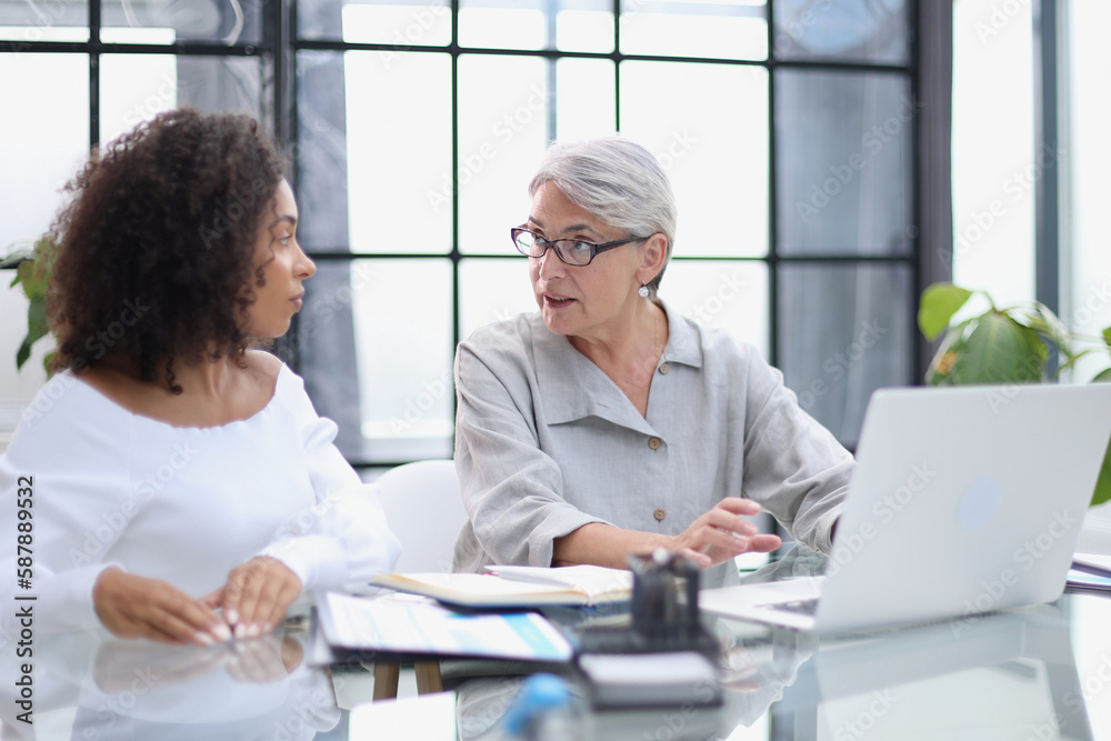 Female colleagues met in the office hall discussing work issues