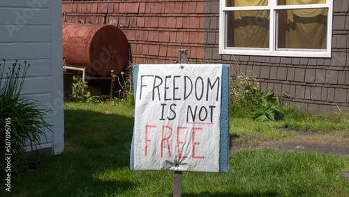 Placard with Freedom is not free inscription. Handwritten placard. Political placard in backyard photo