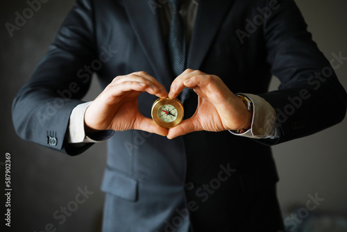 man in suit holding golden compass on gray background