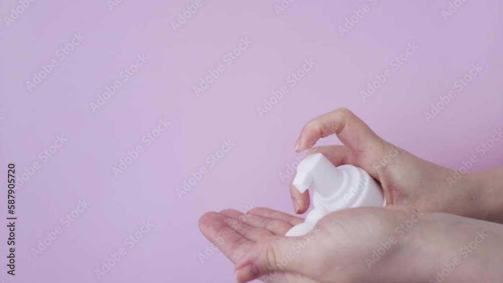 Facial foam dispenser, face wash, cleansing cosmetics, female hand squeezes foam from a bottle into the palm on pink background Facial foam dispenser, face wash, cleansing cosmetics, female hand squeezes foam from a bottle into the palm on pink background