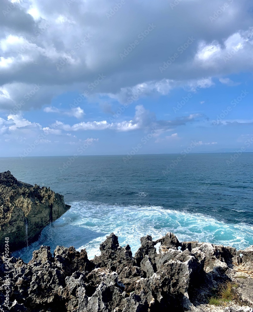 Water blow site in Nusa Dua, where the light sea blue waves of the Indian Ocean constantly crashes against the jagged limestone edges. Sun falling on the limestones adding a shine. 