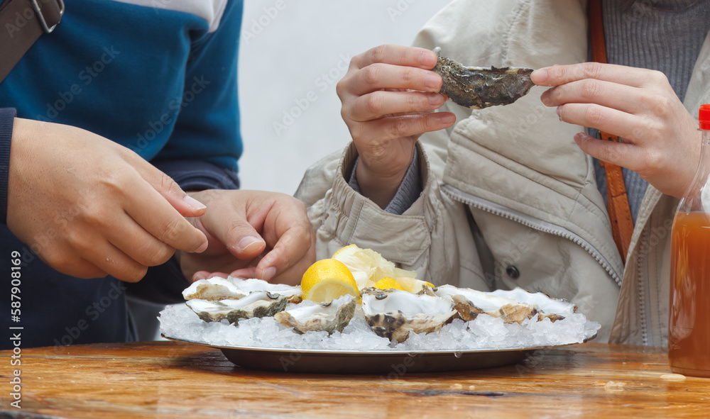 Eating oysters at a street food market, womens hands holding an oyster