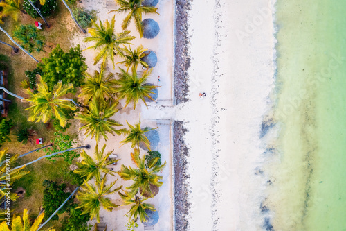 Escape to a tropical paradise with a picture-perfect beach featuring white sand, swaying palm trees, and crystal-clear turquoise waters against a blue sky with fluffy clouds on a sunny summer day.  © Sebastian