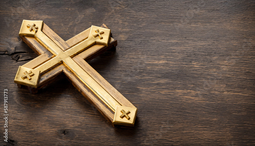 A golden cross lies on a wooden table. Ideal as a banner, wallpaper or header. Space for text. Copy Space, Blank Text.