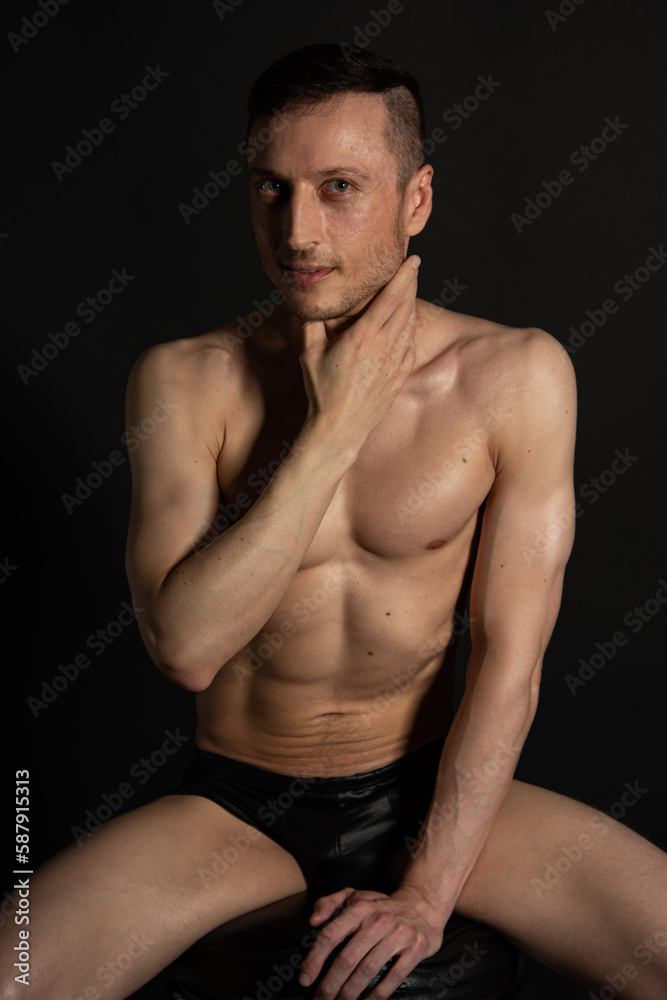 Fototapeta premium Adult attractive man with a beautiful body posing in the studio. Black background.