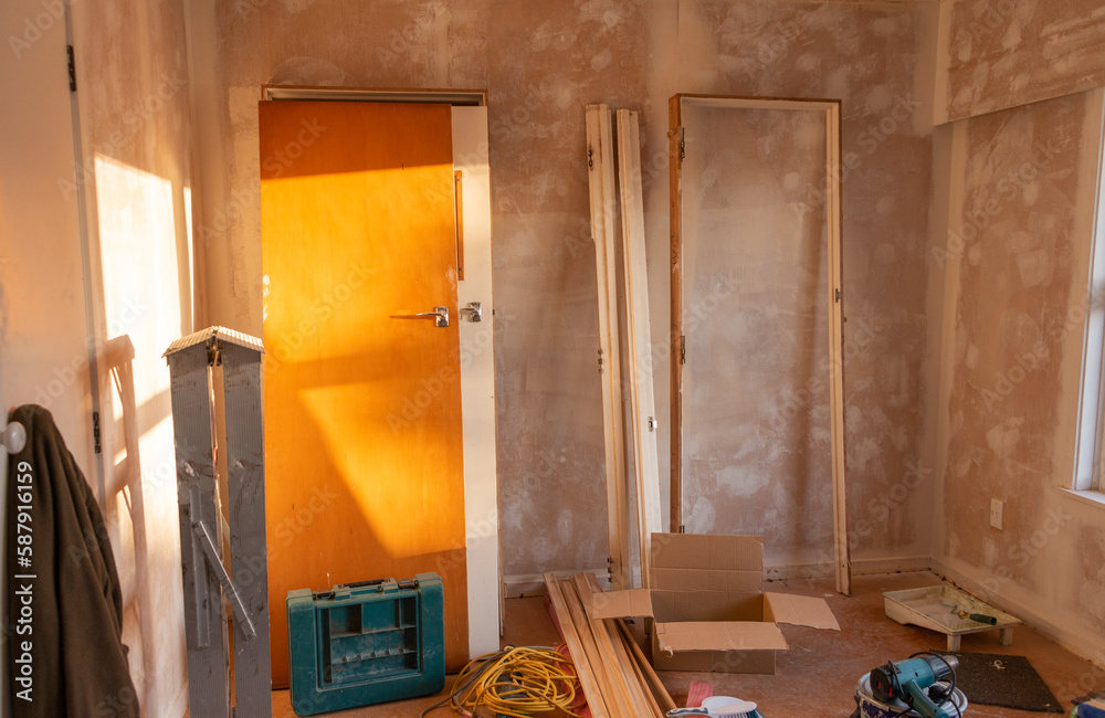 Doors and door frames leaning on the wall. Ladder and tools lying around the room. Home refurbishment project. Auckland.