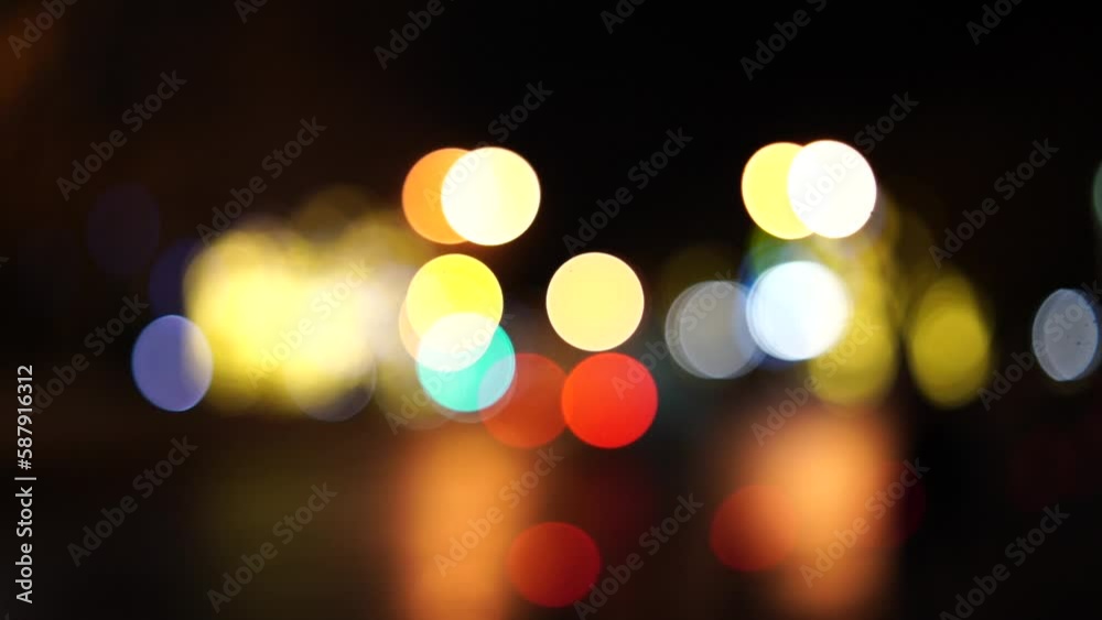 Blurred car lights bokeh in the evening city. Defocused headlights and street lighting at night. Moving bokeh circles of cars at night. Blurred city traffic background