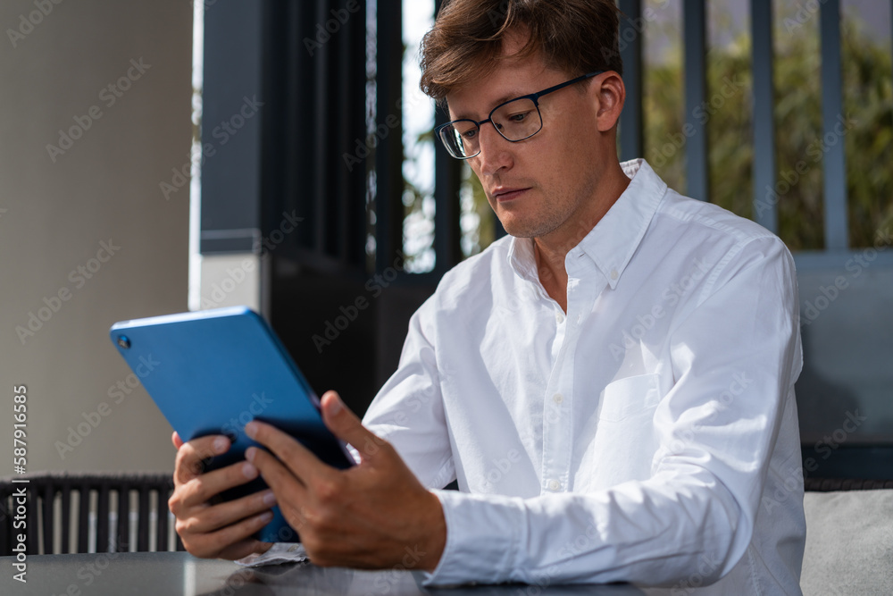 Young man in glasses using tablet computer in office Young man in glasses using tablet computer in office