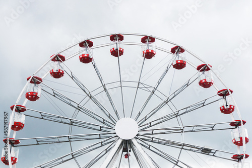 Ferris wheel amusment park. Stormy clouds in the background. Rainy weather ruining festival day in fun park. Funfair adventure background. 