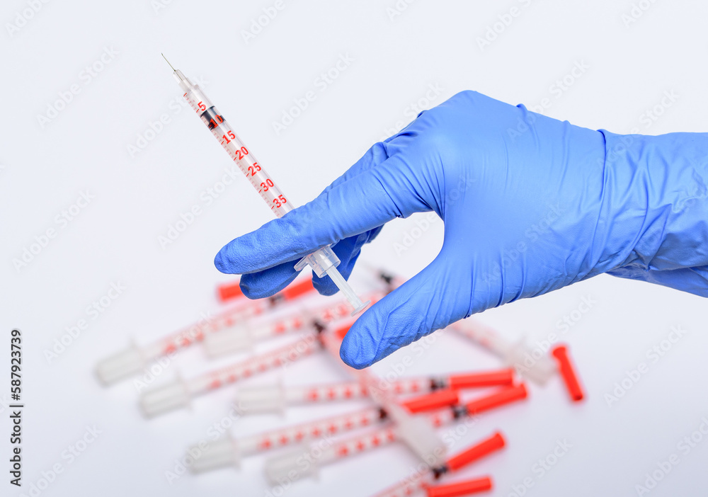 Strzykawka trzymana w dłoni na tle różnych strzykawek w laboratorium Strzykawka trzymana w dłoni na tle różnych strzykawek w laboratorium