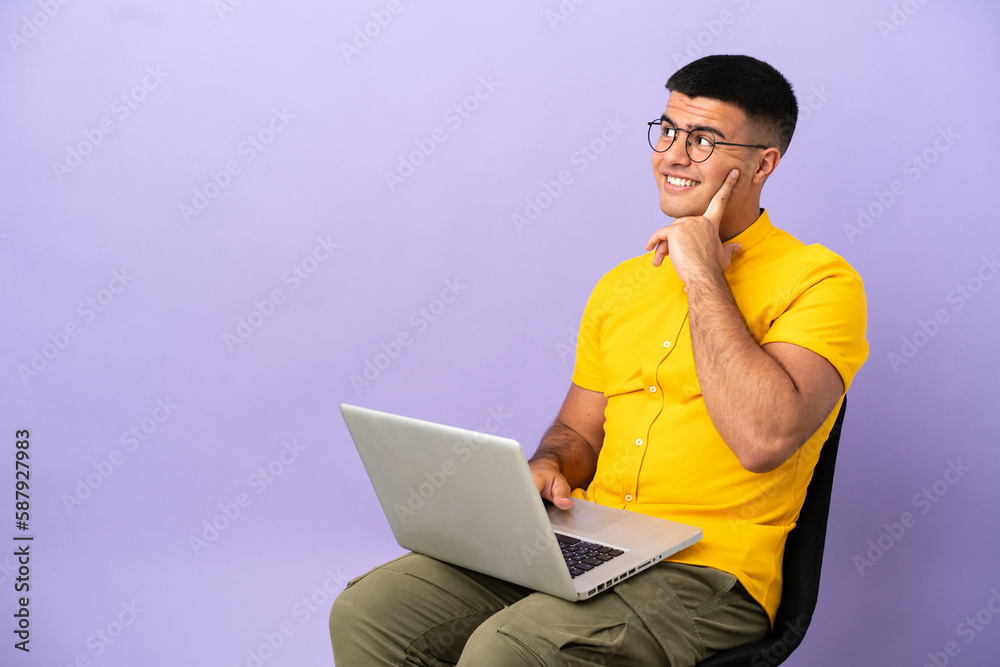 Young man sitting on a chair with laptop thinking an idea while looking up