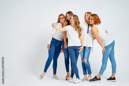 Youth and technology. Full length studio portrait of five beautiful young women laughing and taking selfie on smartphone together.