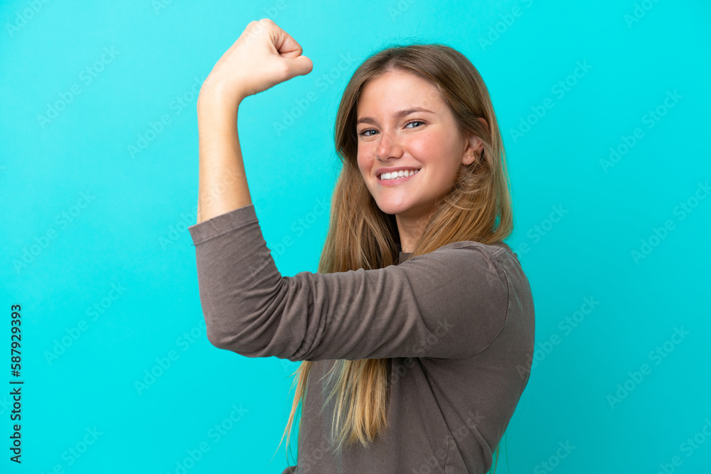 Young blonde woman isolated on blue background doing strong gesture Young blonde woman isolated on blue background doing strong gesture