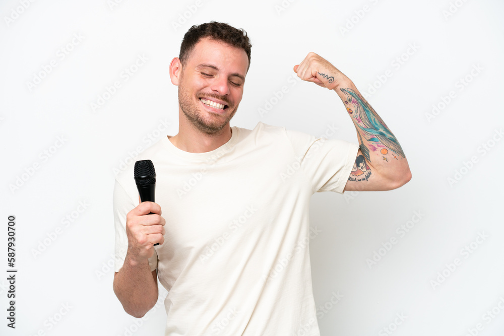 Young caucasian singer man picking up a microphone isolated on white background doing strong gesture Young caucasian singer man picking up a microphone isolated on white background doing strong gesture
