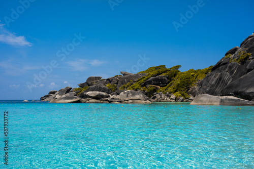 Tropical island of Andaman coast with turquoise and clear blue waters against blue sky.