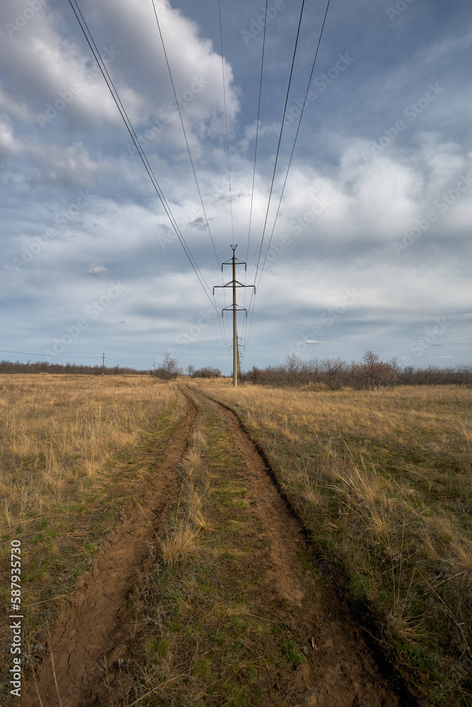 The road stretches into the distance. Power line next to the road going into the distance The road stretches into the distance. Power line next to the road going into the distance