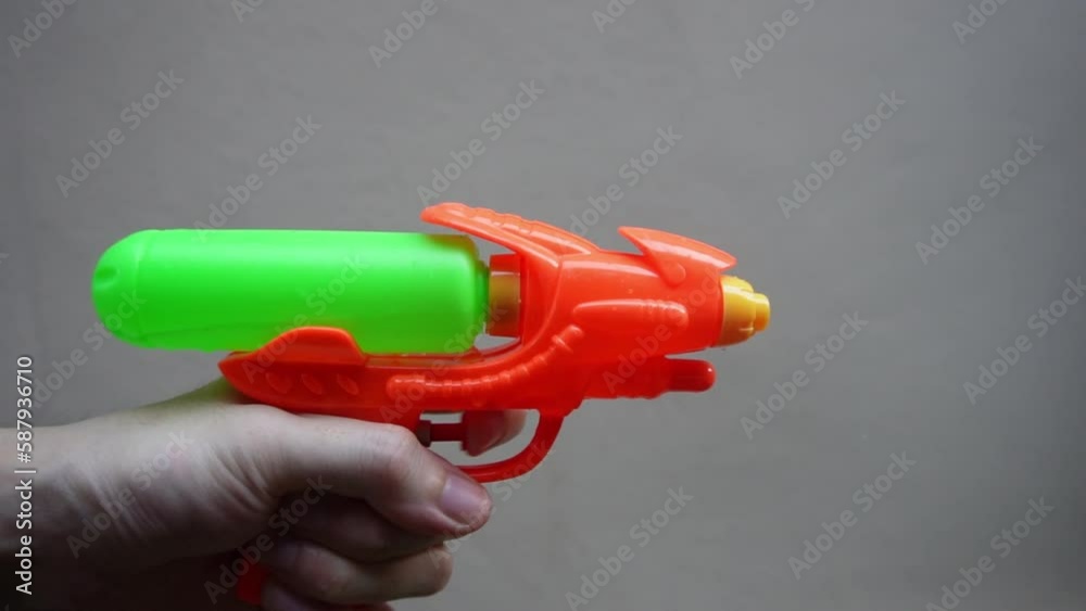 hand holding orange water gun and play with it hand holding orange water gun and play with it