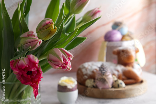 Bouquet of pink tulips on the table against the background of Easter cake and Easter eggs