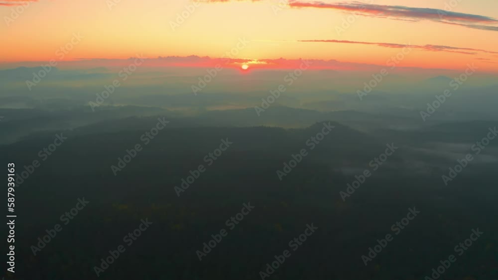 Large forest with green trees in highland at sunset or sunrise. Woods covered with fog under clear sky illuminated with orange sun light aerial view Large forest with green trees in highland at sunset or sunrise. Woods covered with fog under clear sky illuminated with orange sun light aerial view