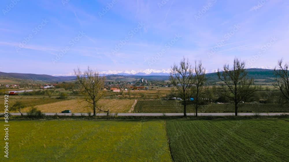 Aerial view over the countryside in Romania at Hosman village, with the fortified church and mountains in the background. Footage was shot from a drone at a lower altitude while flying forward. Aerial view over the countryside in Romania at Hosman village, with the fortified church and mountains in the background. Footage was shot from a drone at a lower altitude while flying forward.