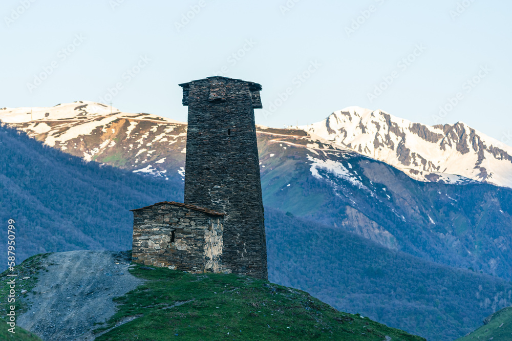 A single Svaneti defense tower in front of the snow-capped Caucasus mountains in Ushguli/ Georgian A single Svaneti defense tower in front of the snow-capped Caucasus mountains in Ushguli/ Georgian
