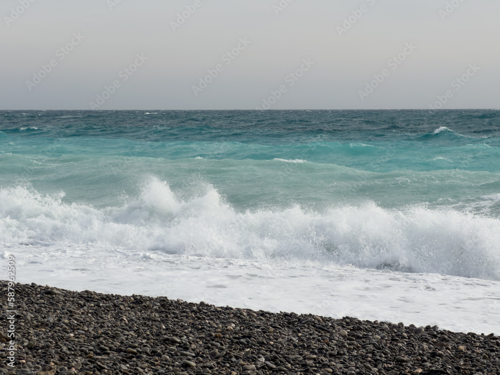 Pebble beach of Nice, France with azure waves of mediterranean sea Pebble beach of Nice, France with azure waves of mediterranean sea