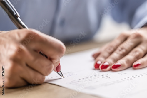 Detail of female hands signing a paper contract or agreement with a pen