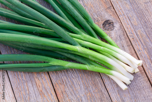 Bunch of fresh green onions on a feather on an old wooden table