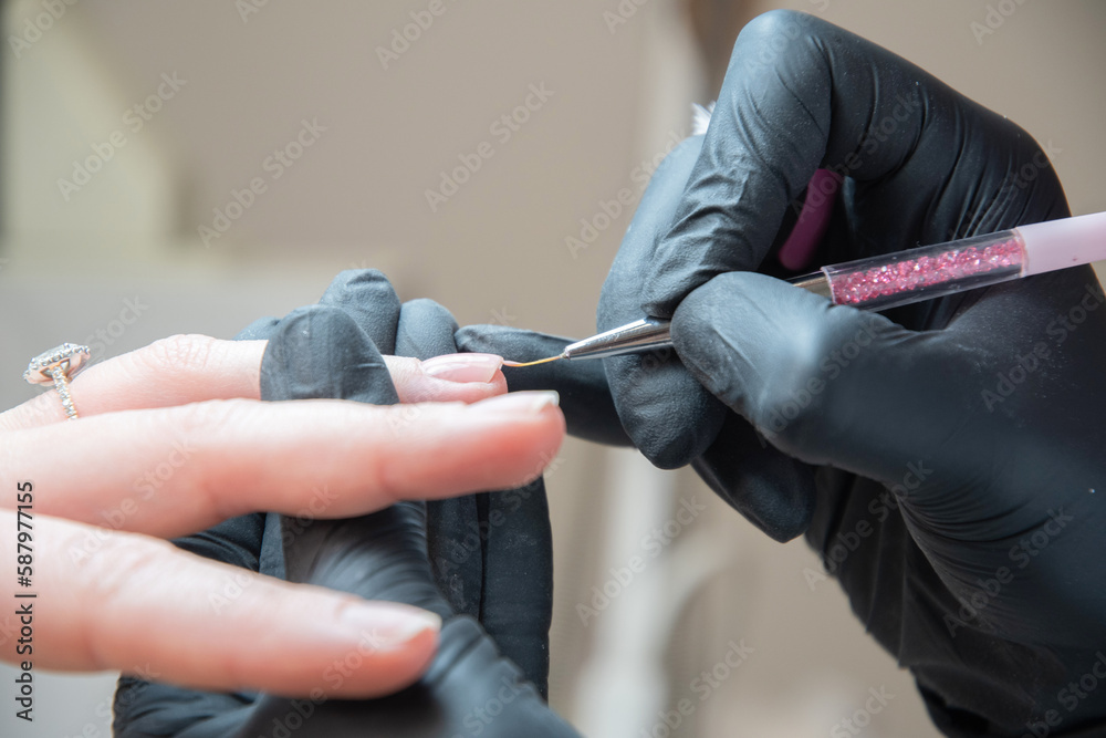 the manicurist levels the edge of the varnish with a thin brush in a salon