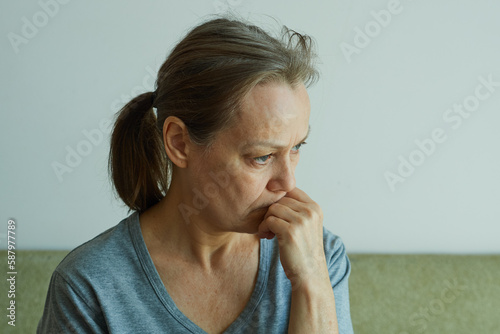 Profile of a pensive, sad mature woman, hand near face
