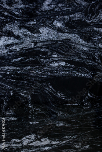 Black spanish matt granite slab with white blured waves Kalahari Black vertical close up