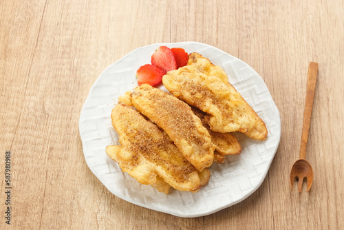 Pisang Goreng or banana fritters with a sprinkling of palm sugar served in white plate. Indonesian food
